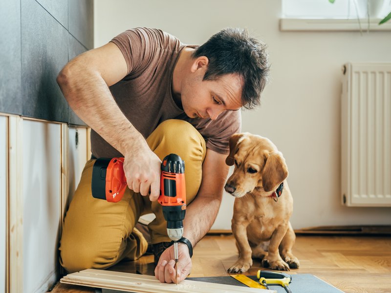 man installing flooring while a puppy watches - Contract Interiors in Fort Wayne, IN