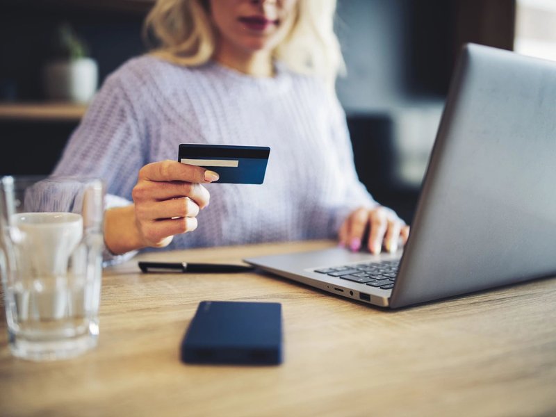 woman holding credit card and on laptop - Contract Interiors, IN