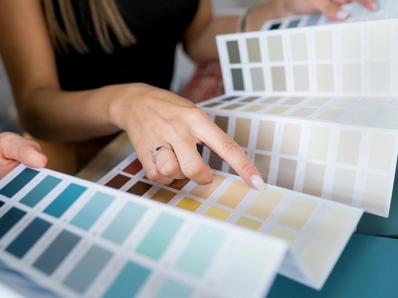 woman choosing paint color from pamphlet - Contract Interiors, IN